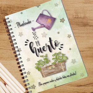 May include: A green and white spiral bound notebook with a watercolor illustration of a watering can pouring water on a potted plant. The notebook cover has the text "Planificador - Mi huerto" and "Para preparar, cuidar y disfrutar todas mis plantas!"
