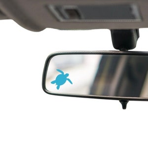 May include: A black rearview mirror with a blue sea turtle sticker on the glass.