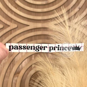 May include: A black and white sticker with the text "passenger prince" and a crown graphic.