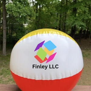 May include: A colorful beach ball with a yellow top, white center, and red bottom. The ball features a logo with geometric shapes and the text "Finley LLC". The ball is outdoors with a green background.