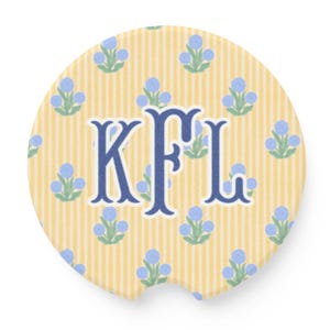 May include: Round car coaster with a yellow and white striped background. The coaster features blue floral accents and the navy blue monogram "KFL" in the center. The coaster has a small notch for easy removal.