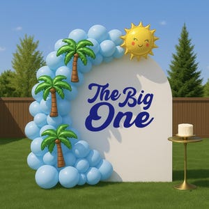 May include: A white arch backdrop with blue balloons, palm tree decorations, and a yellow sun balloon. The text "The Big One" is in blue script. A small cake sits on a gold table. The scene is set outdoors on a green lawn.