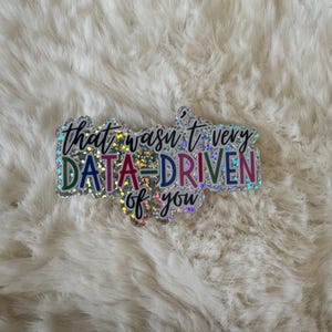 May include: A glittery sticker with the text "that wasn't very data-driven of you". The sticker has a rainbow holographic finish.