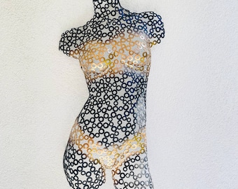 May include: A metal sculpture of a torso made of small, round, interlocking pieces. The sculpture is painted in shades of black and gold.