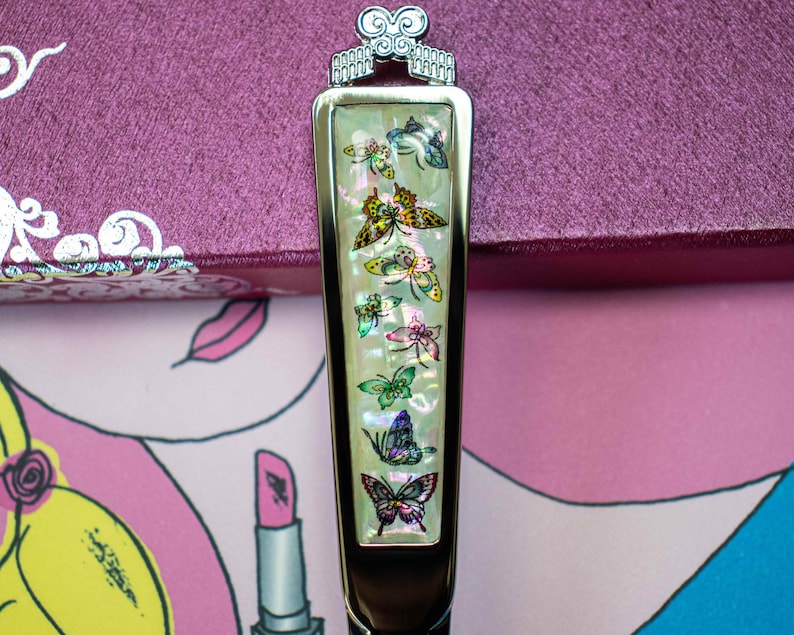 May include: A silver and white butterfly-themed decorative handle with a pearl-like finish. The handle features a series of colorful butterflies with iridescent wings.