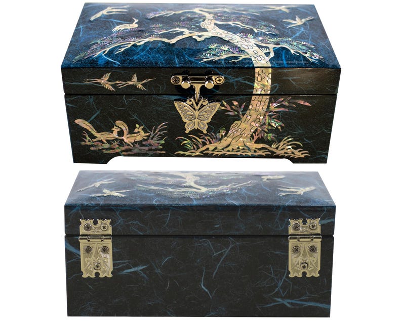 K&ouml;nnte beinhalten: Zwei schwarze dekorative Boxen mit aufwendigen Perlmutt-Inlays. Die obere Box zeigt ein Baum- und Vogeldesign, w&auml;hrend die untere Box Messingbeschl&auml;ge hat. Die Boxen sind rechteckig und haben einen dunkelblauen Hintergrund.