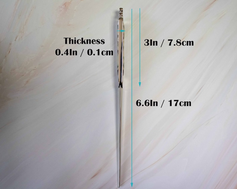 May include: A silver metal knitting needle with a pointed tip. The needle is 6.6 inches long and 0.4 inches thick. The needle is shown against a white background.