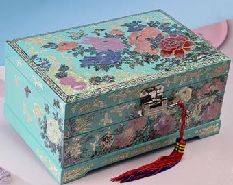 May include: A turquoise wooden jewelry box with a floral design and a silver lock and key. The box has three drawers and is decorated with mother-of-pearl accents.