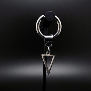 Peut inclure: Une boucle d'oreille en argent avec un cercle et un pendentif en forme de triangle. Le triangle est creux et présente un motif géométrique.