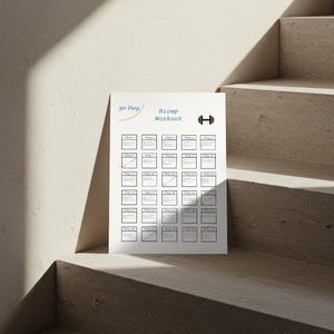 Op de afbeelding: Een witte 30-daagse biceps workout chart met een halter icoon. De chart heeft een raster van vakjes om de voortgang bij te houden, met de dagen van de maand gelabeld. De chart ligt op een lichtgekleurd oppervlak.