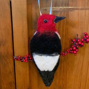 Needle felted Red Headed Woodpecker ornament, he is perched on a berry stem.