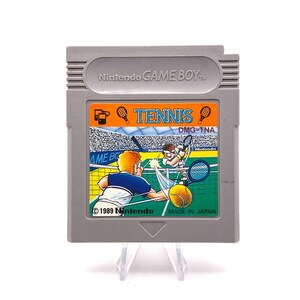 K&ouml;nnte beinhalten: Eine graue Game Boy-Cartridge mit einem bunten Etikett, auf dem zwei Cartoon-Tennisspieler auf einem Platz zu sehen sind. Das Etikett lautet "TENNIS DMG-TNA 1989 Nintendo MADE IN JAPAN".