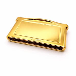 Op de afbeelding: Een goudkleurige, rechthoekige Game Boy-cartridgecase. De case heeft een glanzend, reflecterend oppervlak en een gebogen bovenkant. Het ontwerp omvat een rechthoekig schermgebied en een klein, driehoekig detail nabij de onderste rand. De case is leeg.