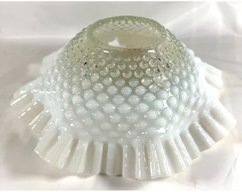 Pode incluir: Um abajur de vidro leitoso branco com uma textura de pontos em relevo por toda a cúpula. O abajur possui uma abertura circular no topo e uma borda larga, franzida e festonada na parte inferior, criando uma silhueta decorativa e alargada.