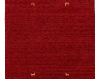 May include: A rectangular red rug with a textured surface. The rug features a repeating pattern of small, tan-colored animal figures and dark brown accents. The rug is suitable for a living room or bedroom.