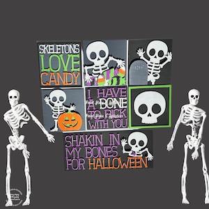 May include: Halloween-themed decorations featuring a white skeleton and several square signs. The signs display phrases like "Skeletons Love Candy" and "Shakin' in my Bones for Halloween" in orange, green, and purple. A carved pumpkin and candy corn are also shown.