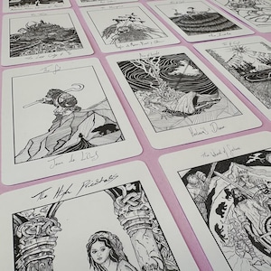 K&ouml;nnte beinhalten: Eine Sammlung von Tarotkarten mit detaillierten Schwarz-Wei&szlig;-Illustrationen. Jede Karte zeigt aufwendige Kunstwerke und handgeschriebene Titel, darunter "Der Narr", "Stab-Ass" und "Die Hohepriesterin". Die Karten liegen auf einer rosa Oberfl&auml;che.