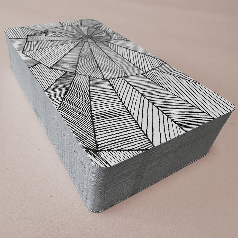 K&ouml;nnte beinhalten: Ein Kartenspiel mit einem geometrischen Schwarz-Wei&szlig;-Design. Die Karten haben graue Kanten und ein Muster aus Linien, die von einem zentralen Punkt ausgehen. Die Karten sind ordentlich gestapelt und zeigen das detaillierte Design auf der obersten Karte.