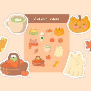 May include: A sheet of stickers with an autumn theme. The stickers feature images of a pumpkin, a ghost, a coffee cup, a basket of apples, a sock, a maple leaf, and a cat. The sheet is titled "Autumn vibes".