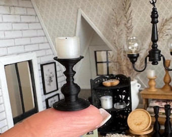 May include: A miniature black candlestick holder with a white candle. The candlestick has a detailed, ornate design. The scene is a dollhouse interior with other miniature furniture and decor.