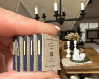May include: A stack of five miniature books with brown covers and blue spines. The book on top has the title "Observations in Oxford" printed on the cover.