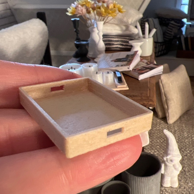 May include: A small, rectangular wooden tray with two cut-out handles. The tray is made of light brown wood and has a natural finish.