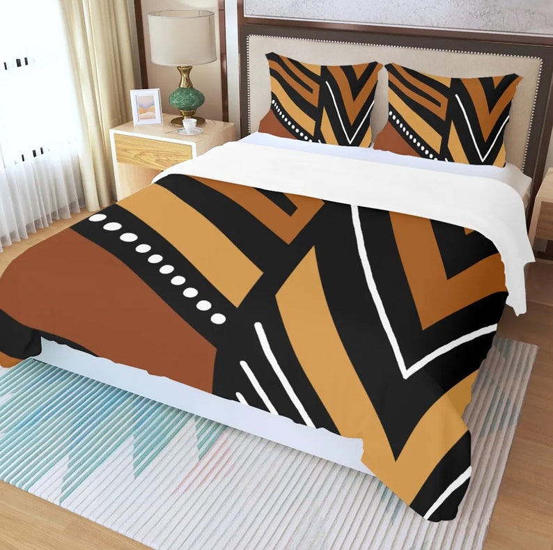 May include: A bed set with a duvet cover and two pillowcases. The bedding features a geometric pattern in shades of brown, black, and tan, with white accents. The design includes stripes, angles, and dotted lines, creating a modern aesthetic.