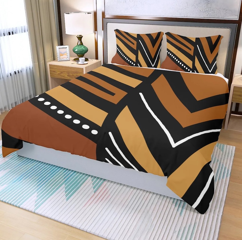 May include: A bed with a duvet cover and two pillowcases featuring a geometric pattern in shades of brown, black, and white. The design includes stripes, rectangles, and a dotted line. The bed is made up with a white bed skirt and sits on a patterned rug.