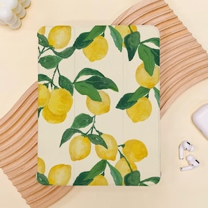 Könnte beinhalten: Eine weiße iPad-Hülle mit einem Zitronen-Druckdesign. Die Hülle zeigt gelbe Zitronen mit grünen Blättern auf weißem Hintergrund.