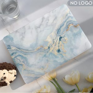Puede incluir: Una funda para portátil con diseño de mármol en tonos azules, blancos y dorados. La funda tiene un acabado liso y brillante. Las palabras "NO LOGO" están impresas en la esquina superior derecha.