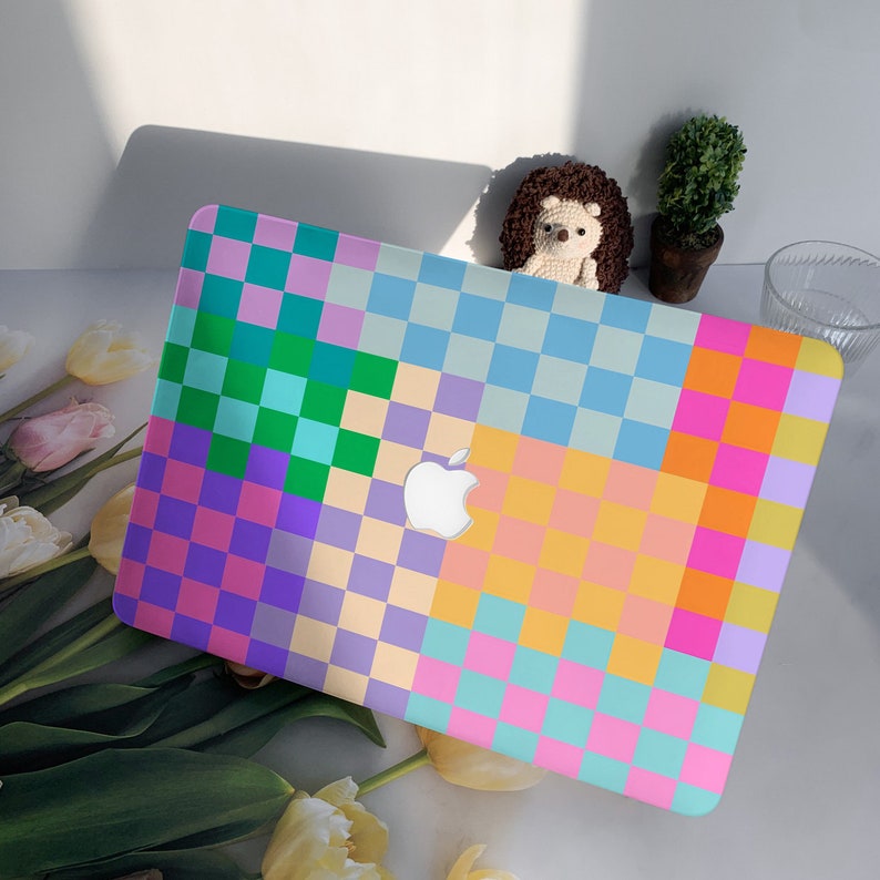 K&ouml;nnte beinhalten: Ein Laptop mit einer bunten karierten H&uuml;lle. Die H&uuml;lle besteht aus Quadraten in den Farben Rosa, Lila, Gr&uuml;n, Blau und Gelb.