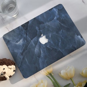 May include: A blue marble laptop skin with a white Apple logo. The skin has a textured, marbled pattern.