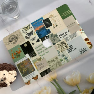 Peut inclure: Un ordinateur portable avec un collage d'images et de texte. Les images comprennent des papillons, des fleurs et une ville. Le texte comprend des citations sur la croissance, se permettre de grandir et faire confiance à son parcours. L'ordinateur portable est sur une surface blanche.