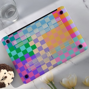 K&ouml;nnte beinhalten: Eine bunte karierte Laptop-Haut mit einer Vielzahl von Pastellfarben, darunter Rosa, Blau, Gr&uuml;n und Gelb. Die Haut hat ein kariertes Muster mit einer Vielzahl von Quadraten unterschiedlicher Gr&ouml;&szlig;e.