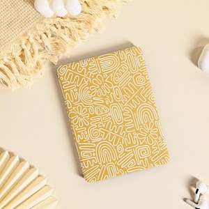 Peut inclure: Un carnet jaune avec un motif abstrait blanc. Le carnet est sur une surface beige clair.