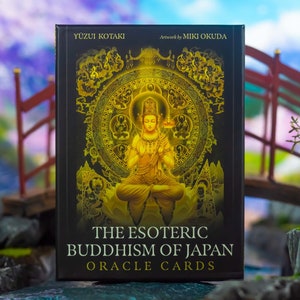 May include: A deck of oracle cards titled "The Esoteric Buddhism of Japan" with artwork by Miki Okuda. The card box is black with gold illustrations of a seated Buddha and a decorative circular design. The text "Yuzui Kotaki" is at the top.