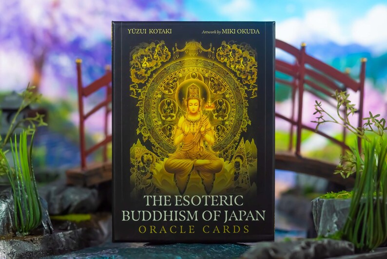 May include: A deck of oracle cards titled "The Esoteric Buddhism of Japan" with artwork by Miki Okuda. The card box is black with gold illustrations of a seated Buddha and a decorative circular design. The text "Yuzui Kotaki" is at the top.