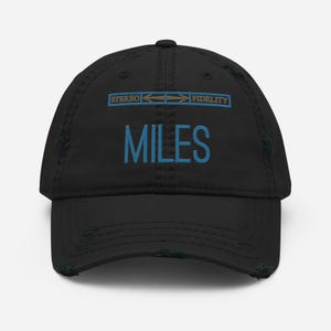May include: Black distressed baseball cap with the text "STEREO FIDELITY" and "MILES" embroidered in brown and blue thread.