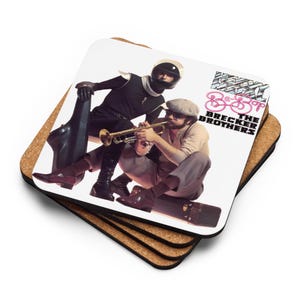 May include: Square coaster featuring a vintage album cover with two men, one playing a trumpet. The album cover reads "Brecker Brothers" in pink and white text. The coaster is made of cork and has a white surface.