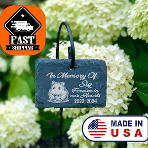May include: Black slate garden stone memorial with the text "In Memory Of Sig Forever in our Hearts 2022-2024" and a small image of a hamster. The stone is attached to a black metal stake.