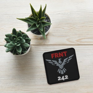 May include: Black embroidered patch with a gray eagle design and the text "FRNT 242" in red.