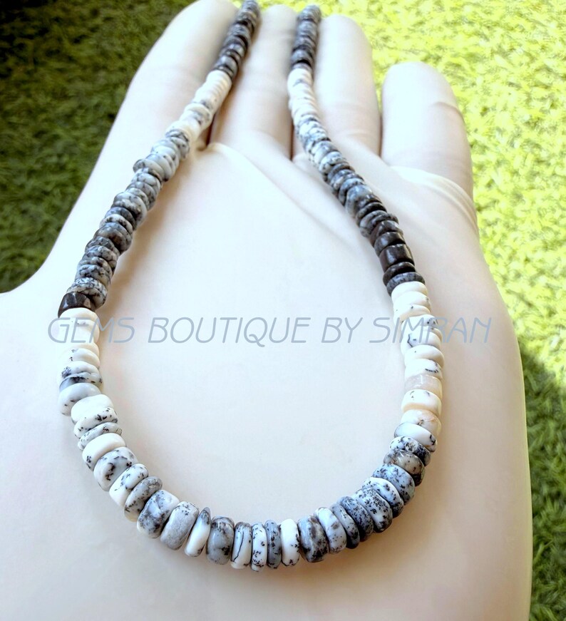 May include: A necklace composed of small, disc-shaped beads in alternating patterns of solid white and mottled gray and black. The beads are strung in a circular arrangement, featuring a repeating color sequence throughout the entire length of the strand.