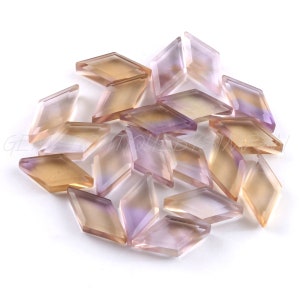 May include: A pile of 18 faceted amethyst and citrine gemstone chips in a kite shape. The chips are a mix of light purple and yellow.
