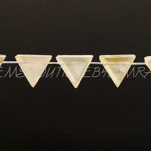 May include: A strand of six iridescent white triangle-shaped beads. The beads are strung on a clear thread.