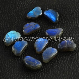 Puede incluir: Una colección de diez cabujones de labradorita azul en forma de nube. Las piedras son iridiscentes y tienen una variedad de tonos de azul.