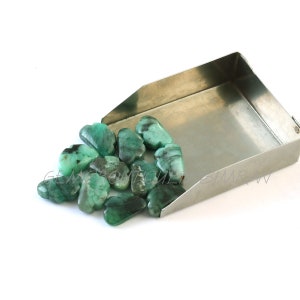 Pode incluir: Um grupo de 15 cabochões de pedra preciosa verde esmeralda em forma de nuvem, espalhados em uma bandeja de metal. As pedras preciosas são de cor verde escura com inclusões pretas.