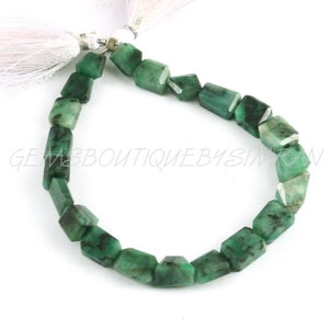 May include: A strand of emerald green gemstone beads, each bead is faceted and has a rectangular shape. The beads are strung on a white cord and are ready to be used for jewelry making.