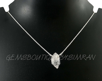 May include: A silver chain necklace with a clear quartz crystal pendant. The crystal is raw and has a natural, irregular shape.
