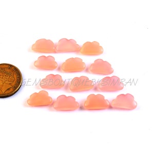 May include: A collection of 12 pink cloud shaped cabochons. The cabochons are smooth and polished. They are approximately 1 inch in size.
