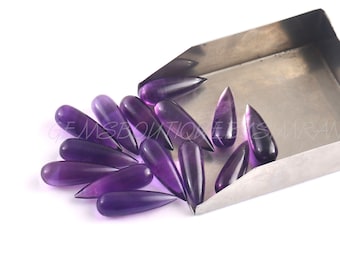 May include: A group of purple amethyst teardrop shaped gemstones in a metal scoop.